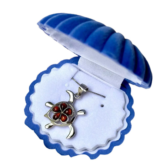 A silver necklace with a pendant in the shape of a turtle, displayed in a blue and white box.