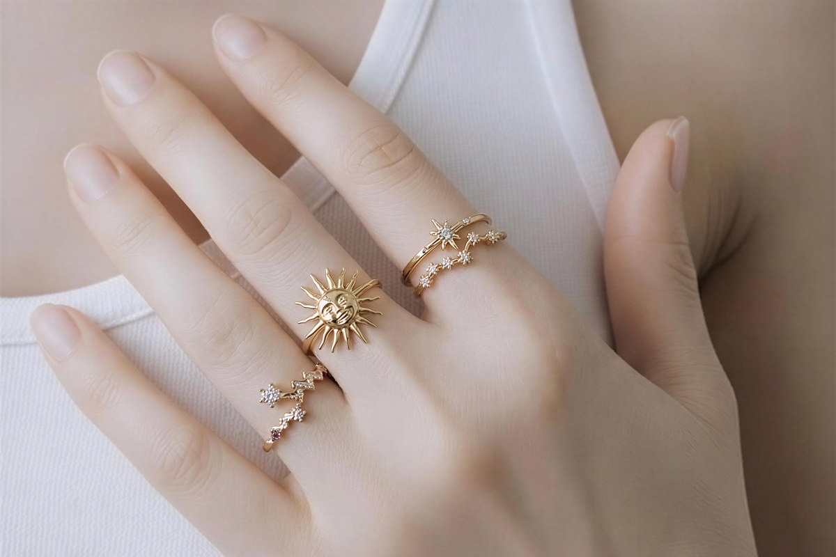 A close-up of a person's hand wearing three gold rings on the fingers.