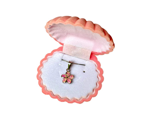 A pink and white shell-shaped jewelry box containing a silver flower-shaped pendant.