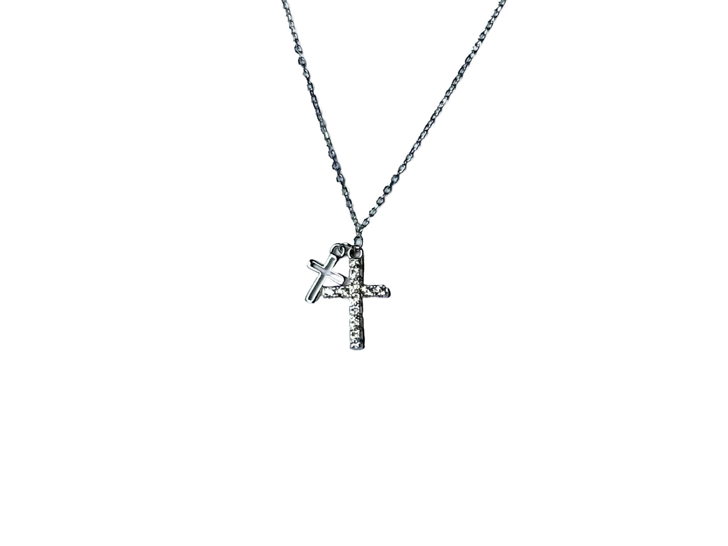 A silver cross pendant with a small charm attached to it.