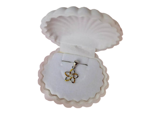 A necklace pendant is displayed in a white, scalloped-edge box, which is open to reveal the pendant inside.
