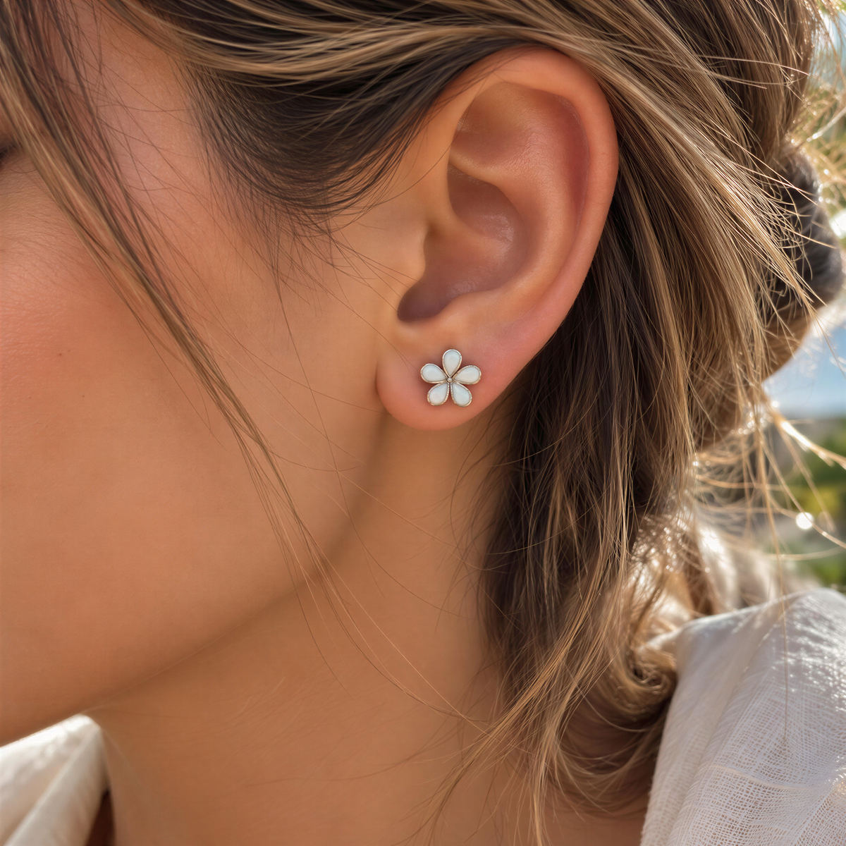 A close-up of a person's ear with a small flower-shaped earring.