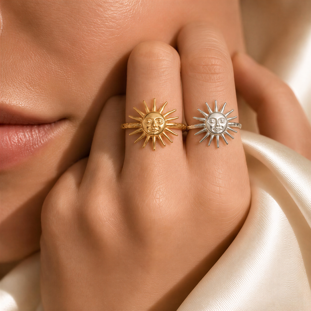 A close-up of a person's hand wearing two rings with sun-like designs.
