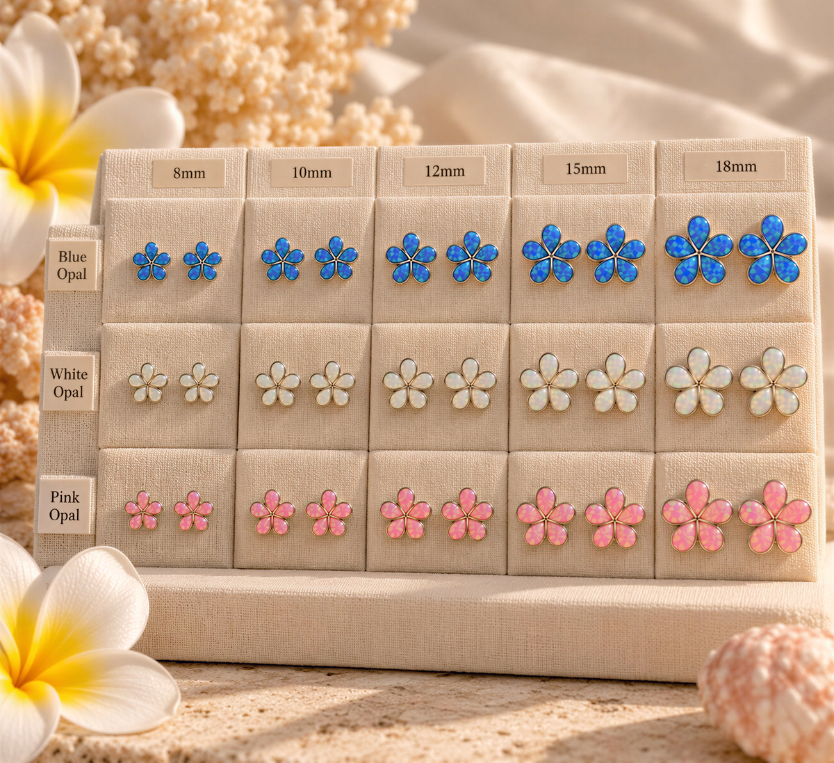A display case with various sizes of blue and pink flower earrings, each labeled with the corresponding size in millimeters.
