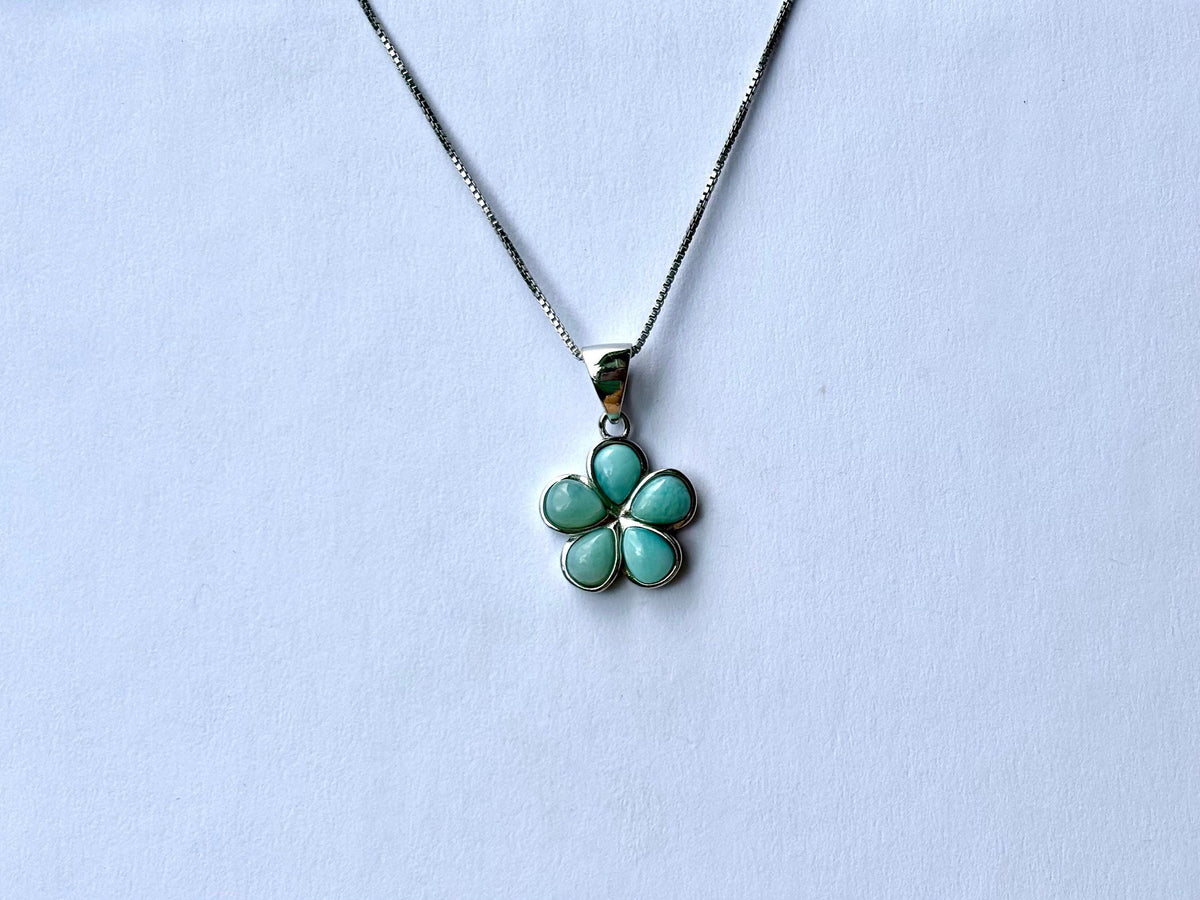 A silver necklace with a pendant featuring a blue flower-shaped gemstone.