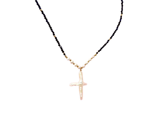 A necklace with a large cross pendant made of black beads and white beads.