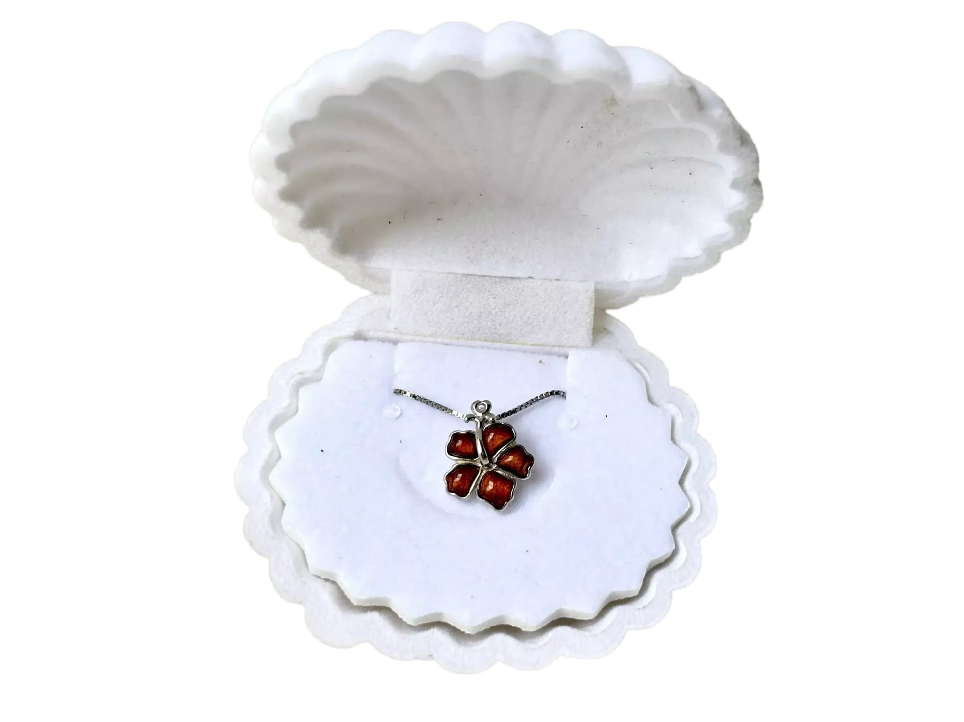 A necklace with a pendant is displayed in a white, scalloped-edge jewelry box.