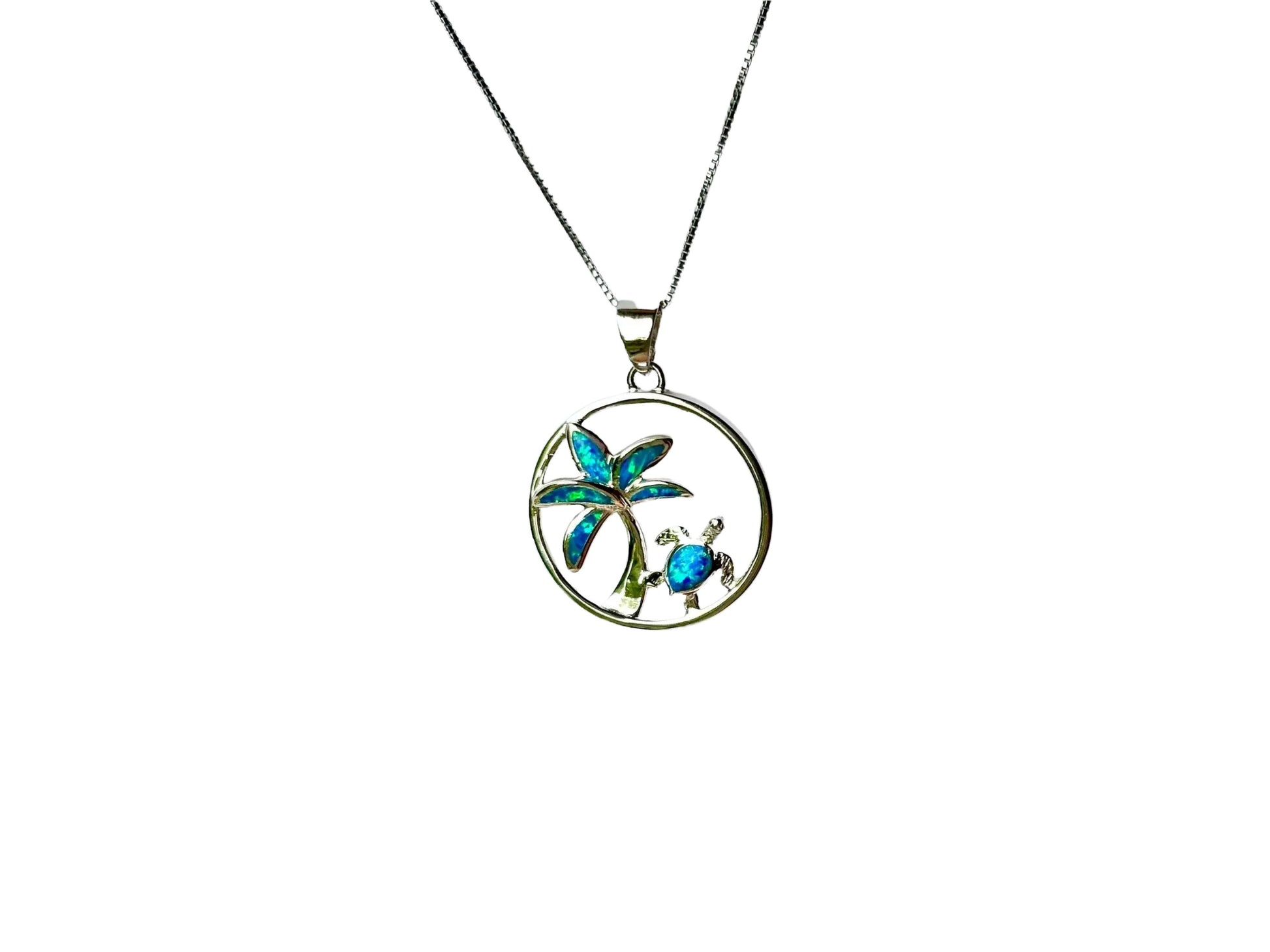 A silver pendant necklace with a circular design featuring a palm tree and a turtle.