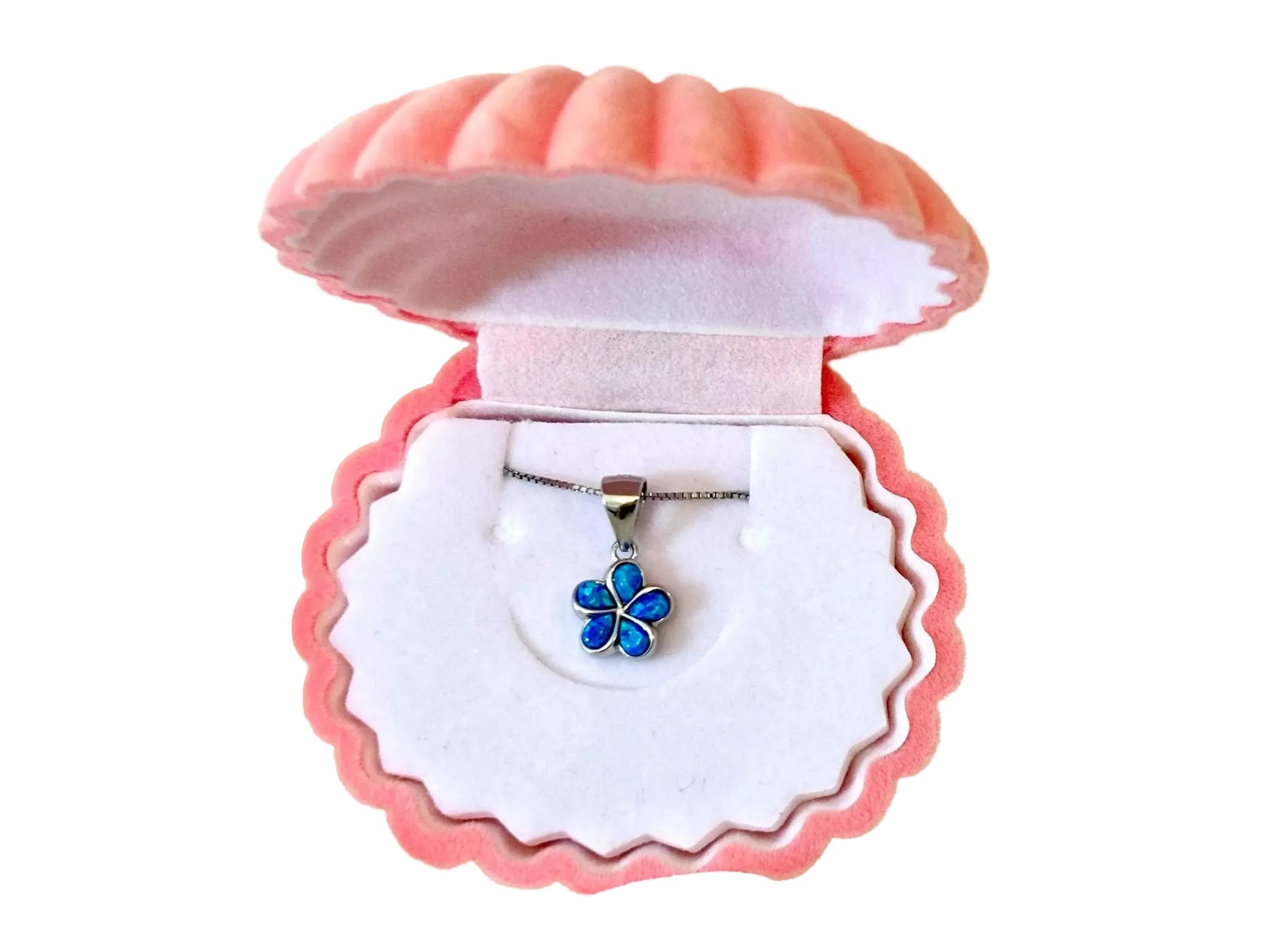 A pink shell-shaped jewelry box containing a necklace with a blue flower pendant.