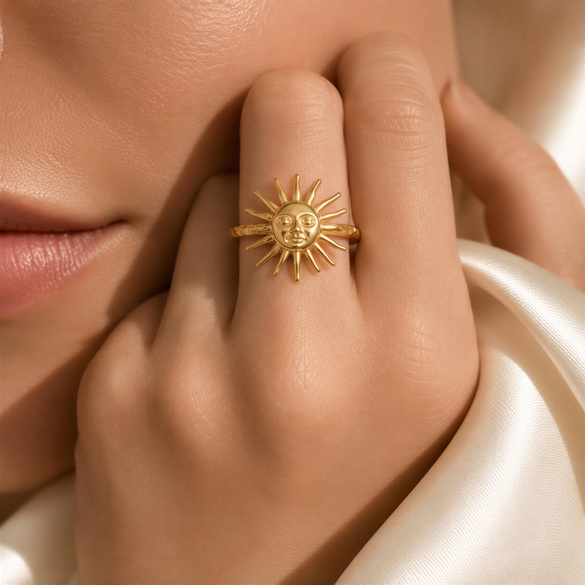 A close-up of a person's hand wearing a gold ring with a sun design.