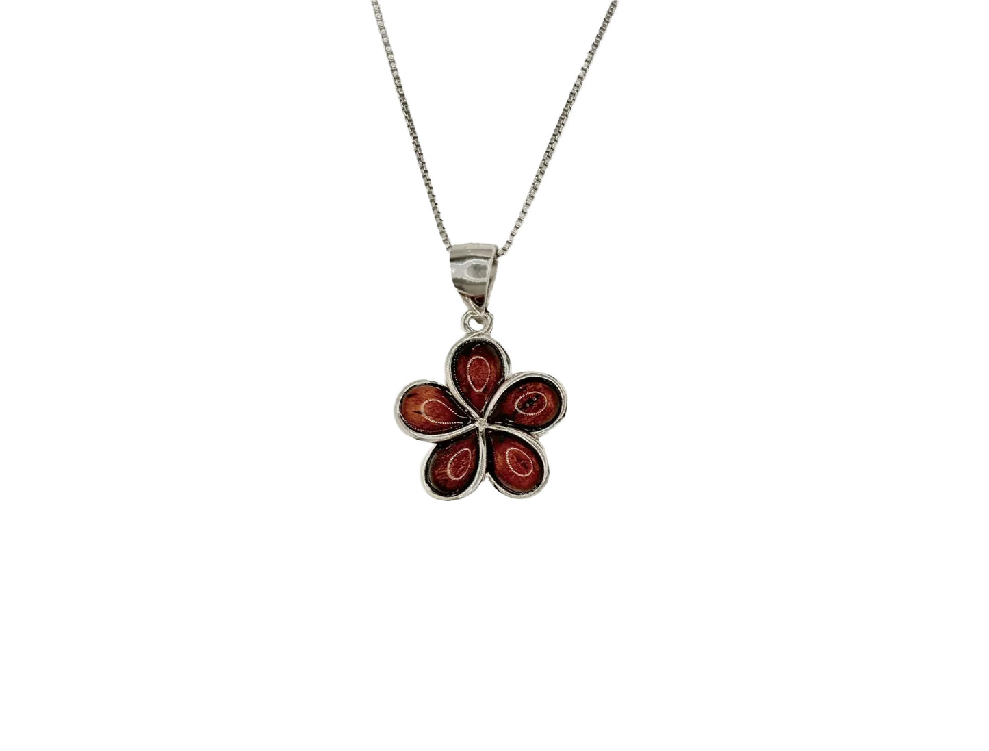 A silver necklace with a pendant featuring a red flower design.