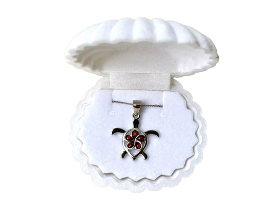 A silver necklace pendant with a red flower design, displayed in a white shell-shaped jewelry box.