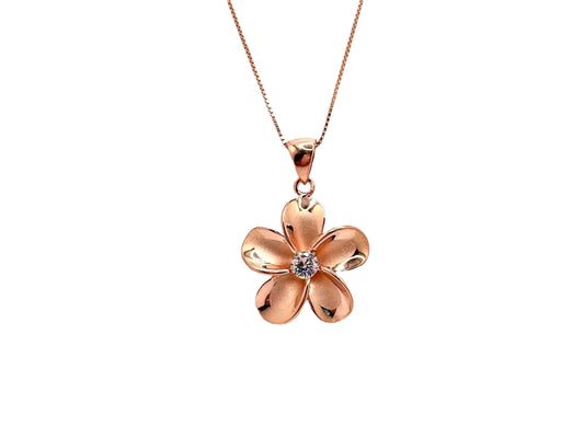 A delicate gold-colored pendant necklace with a single, intricately designed flower-shaped charm featuring a small gemstone at its center.
